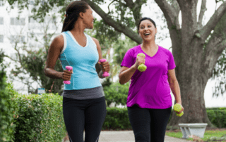 Two woman jogging while holding dumbbells