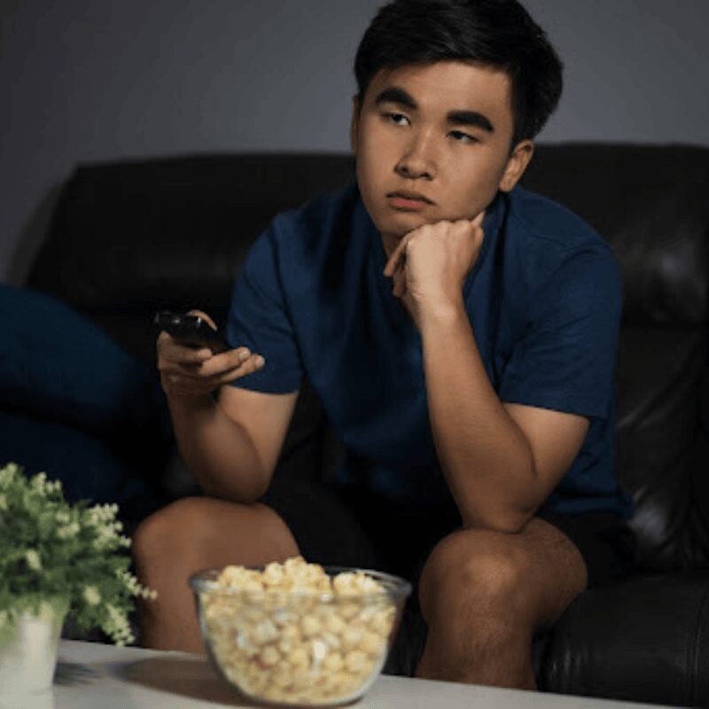boy sitting on couch tv remote in hand